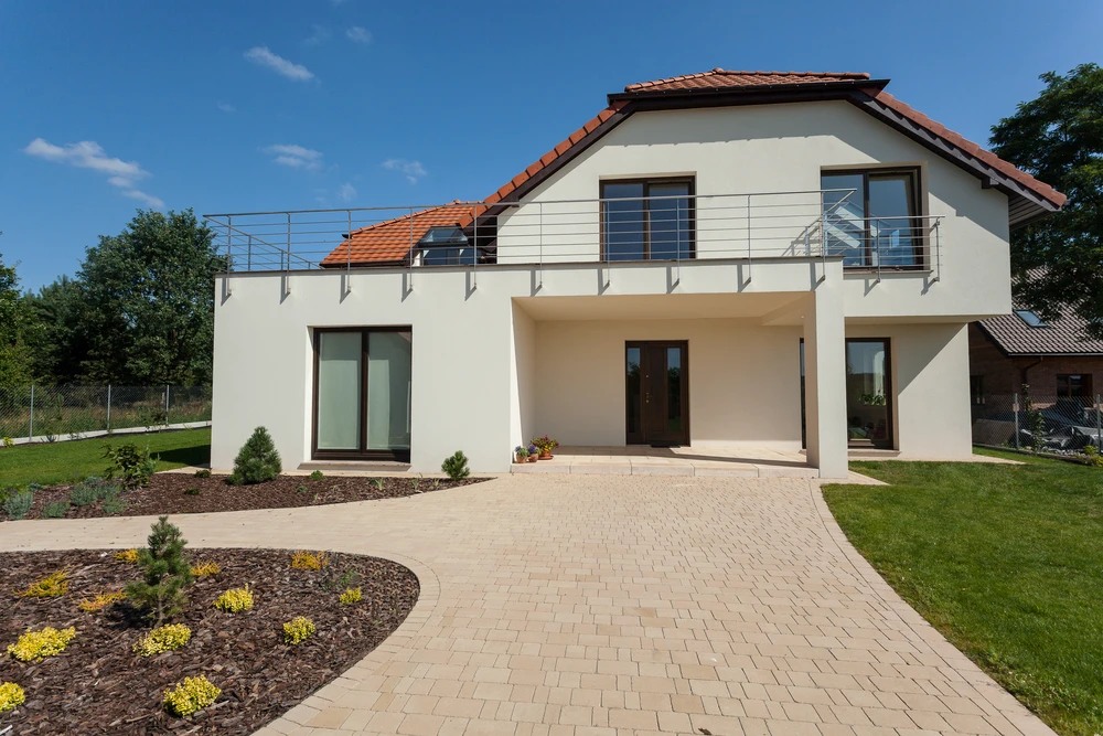 Maison contemporaine à deux niveaux avec balcon et terrasse couverte, façade enduit blanc, toiture tuiles terre cuite, baies vitrées modernes
