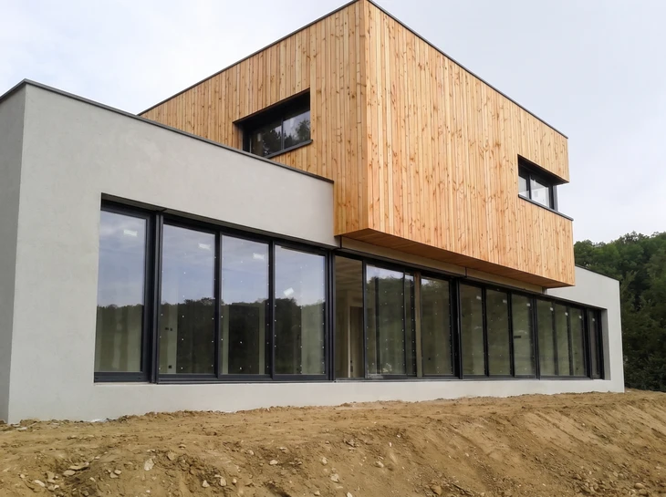 Maison contemporaine unifamiliale avec façade blanche et soubassement gris anthracite, située sur terrain paysager avec pelouse