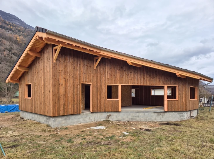 Maison écologique miniature recouverte de gazon avec panneaux solaires photovoltaïques sur toiture, située dans paysage verdoyant avec arbre et oiseau en vol