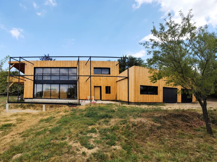 Maison contemporaine à deux niveaux avec terrasse couverte, mobilier coloré extérieur, pelouse entretenue et aménagement paysager